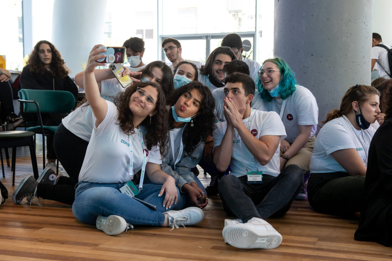 12 students sitting on the floor posing for a selfie