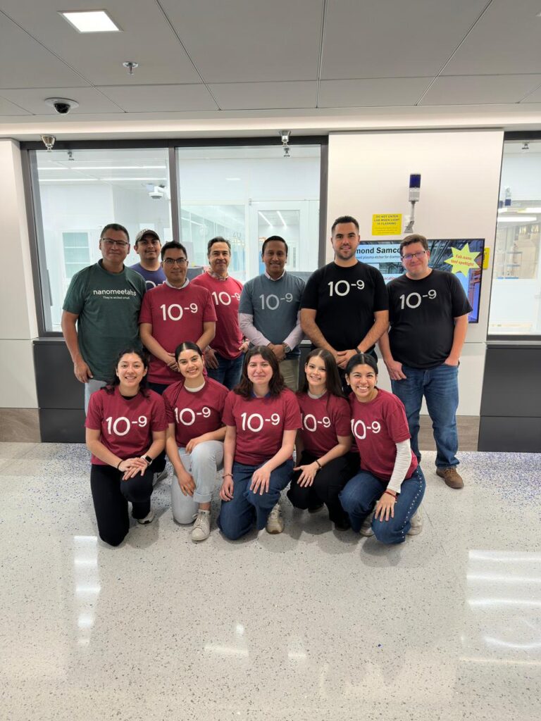 Twelve people smile before MIT.nano's cleanroom